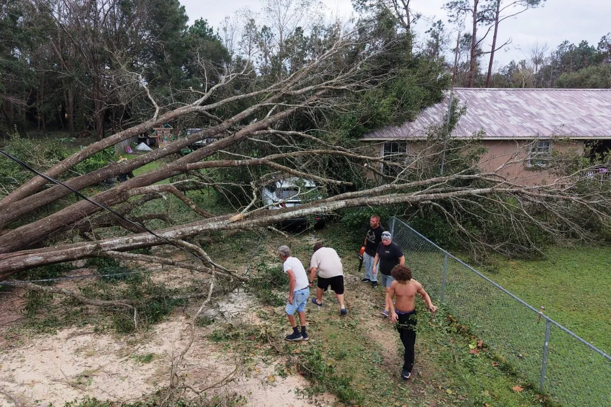 Một nhóm người dân dọn dẹp cây đổ trước một ngôi nhà ở Milton, bang Florida ngày 10-10 - Ảnh: AP