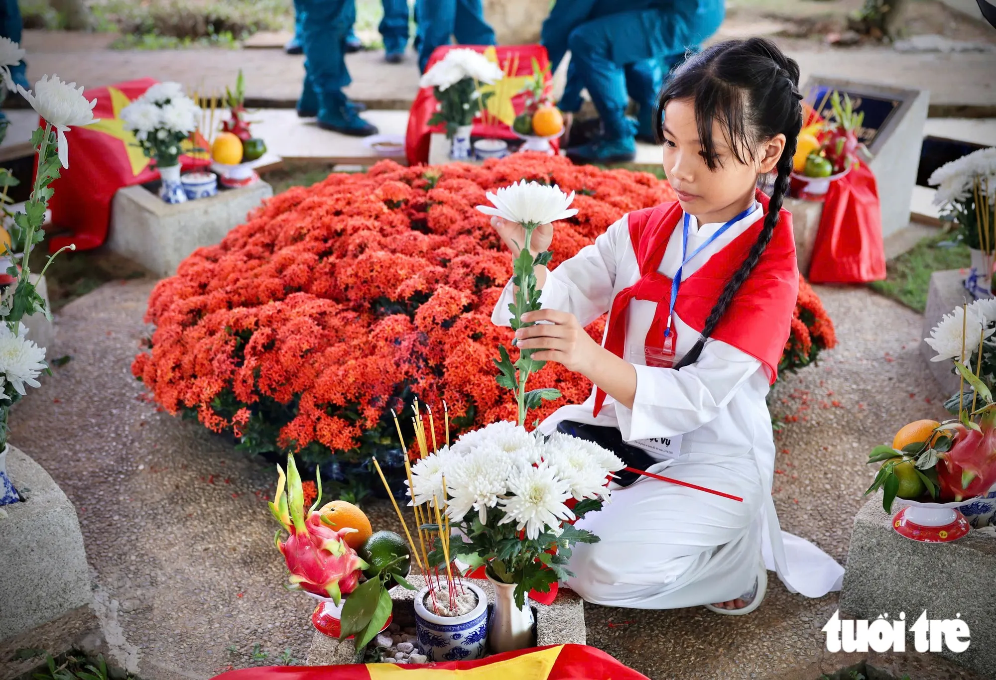 Bé My, một trong những em bé có mặt ở Nghĩa trang liệt sĩ TP.HCM hôm nay đang đặt những bông hoa cúc trắng lên phần mộ các liệt sĩ  - Ảnh: NGUYỄN KHÁNH