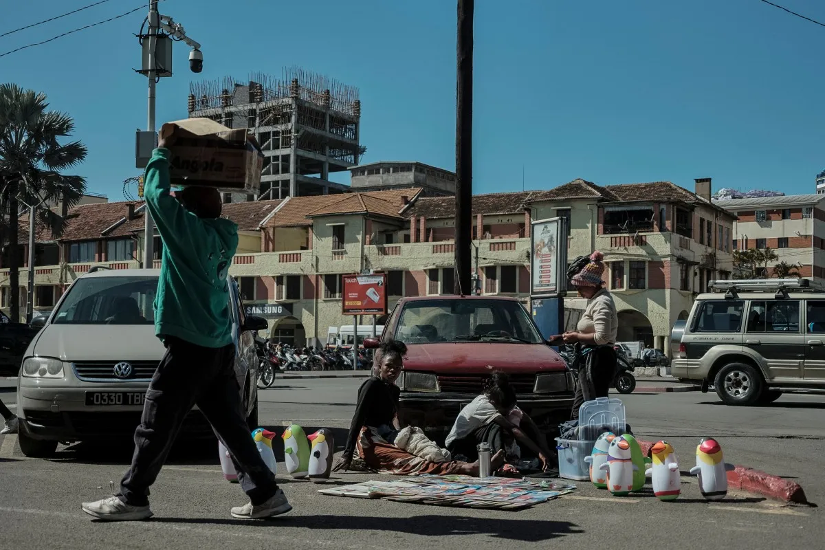 Một người đàn ông đi ngang qua người bán hàng rong tại khu phố Analakely, thủ đô Antananarivo, Madagascar ngày 17-9-2026 - Ảnh: AFP