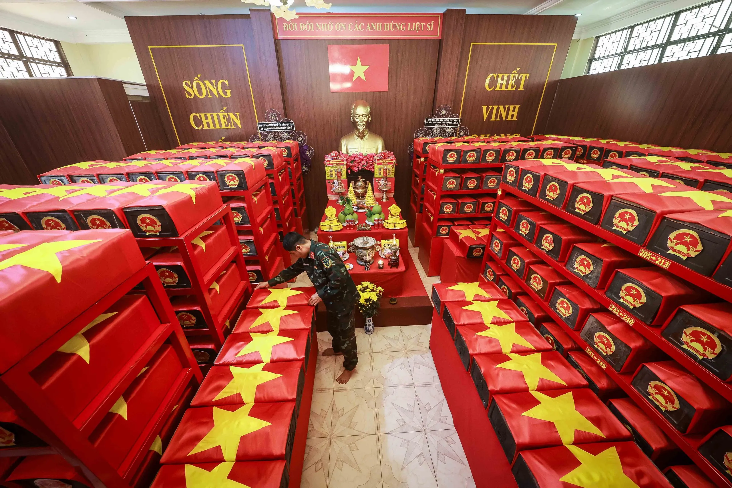 Trung tá Trần Đức Thuận đang chỉnh lại Quốc kỳ được phủ trên tiểu quách chứa hài cốt các liệt sĩ được tìm thấy tại công viên Lê Thị Riêng - Ảnh: NGUYỄN KHÁNH