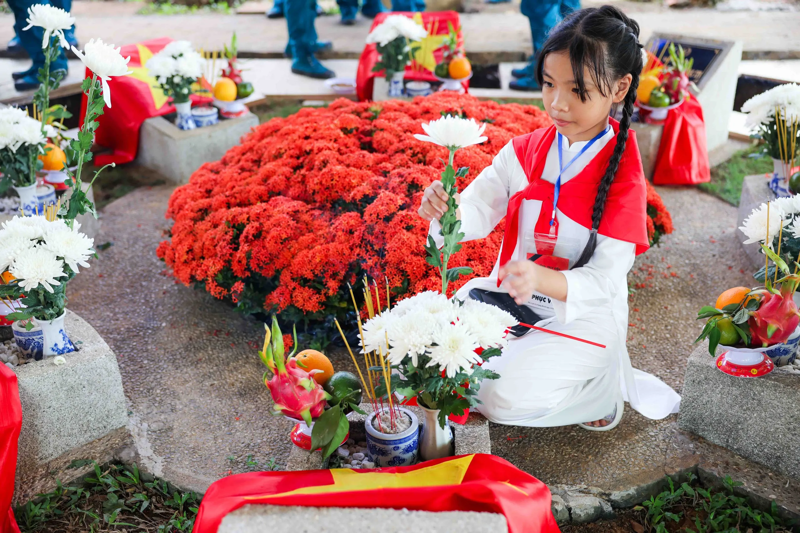 Bé My, một trong những em bé có mặt ở Nghĩa trang liệt sĩ TP.HCM, đang đặt những bông hoa cúc trắng lên phần mộ các liệt sĩ - Ảnh: NGUYỄN KHÁNH