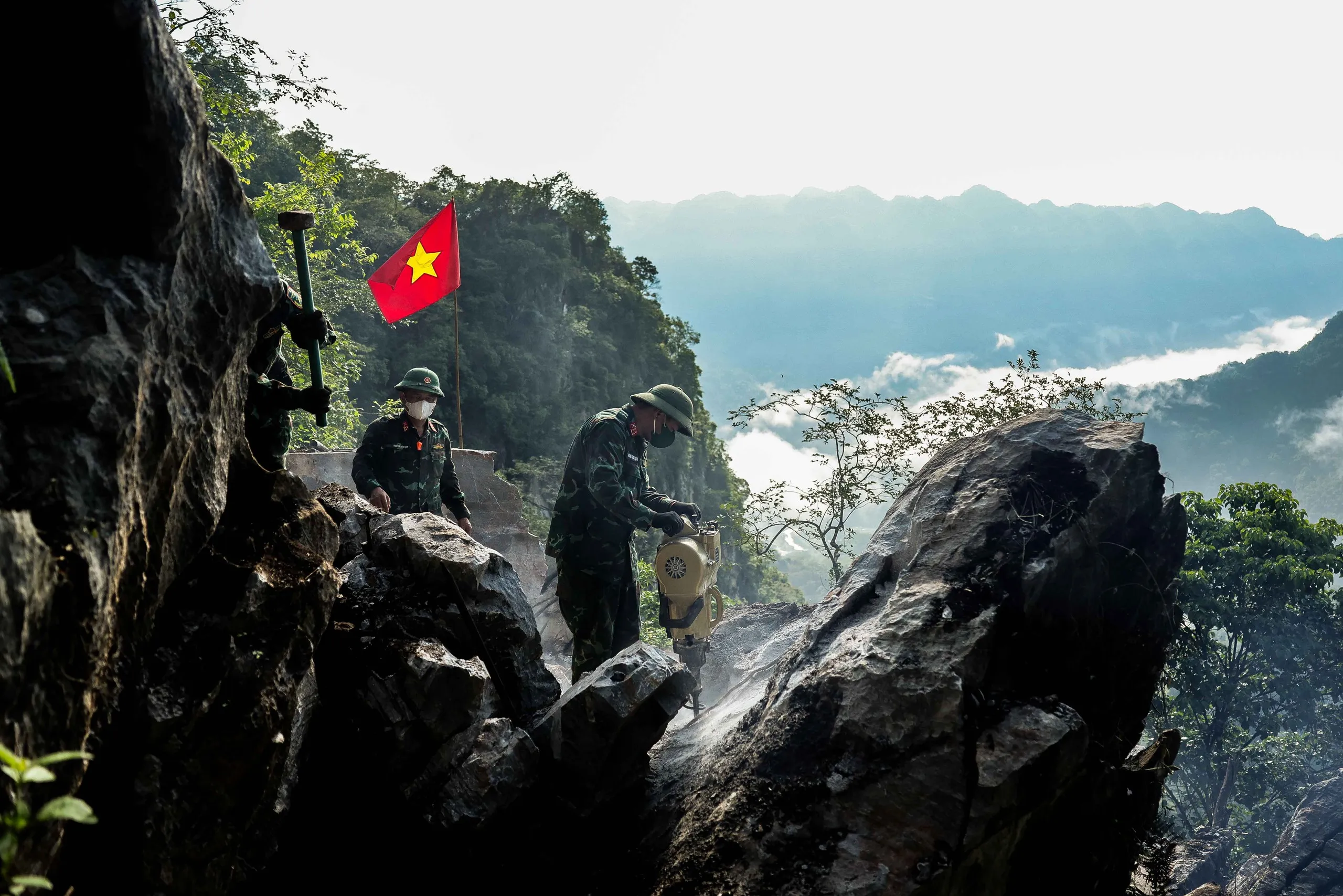 Giữa thời tiết nắng nóng, các thành viên tổ tìm kiếm miệt mài phá đá tìm đường vào hang đá sập - Ảnh: NGUYỄN KHÁNH