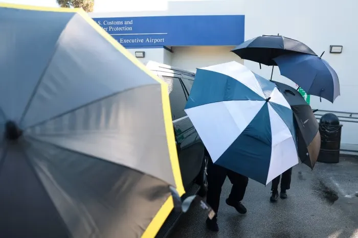 Các sĩ quan cảnh sát dùng ô che chắn khi gia đình ông Bolsonaro rời sân bay ở thành phố Miami.