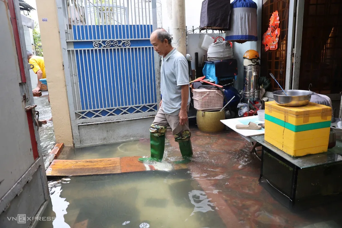 Ngoài hiên, chỗ trũng ngập gần 40 cm, ông Minh kê những tấm ván gỗ làm lối đi tạm.