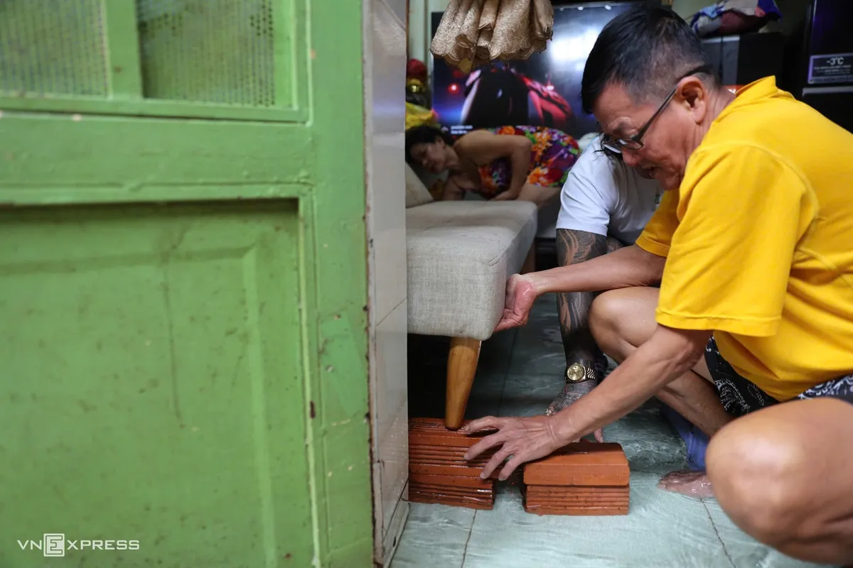 Nhà bên cạnh, ông Từ Đình Khôi nâng bộ ghế sofa khỏi mặt nước để có chỗ sinh hoạt. Theo ông, nhiều năm nay, khu vực này thường xuyên ngập sâu, mỗi lần nước tràn vào phải chờ rất lâu mới rút.