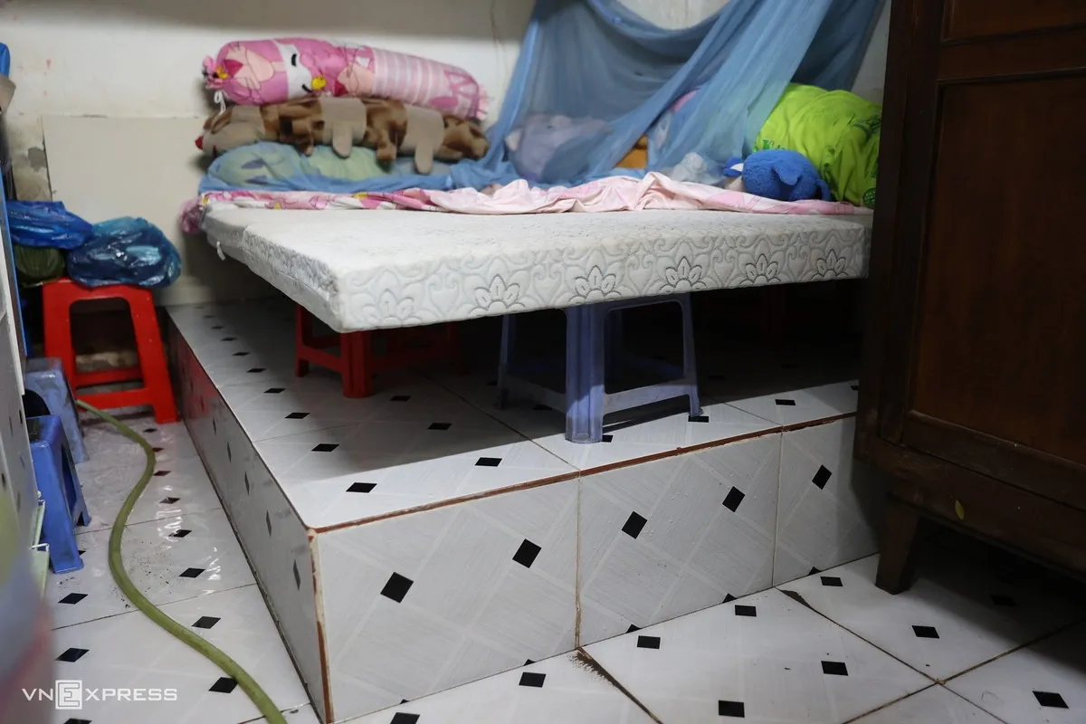 Dù chỗ ngủ nằm trên nền gạch cao hơn sàn nhà, bà Trúc vẫn phải dùng nhiều ghế nhựa kê thêm bên dưới tấm nệm để tránh ướt. Chăn, gối được gom lên trên, phía dưới còn đọng nước.