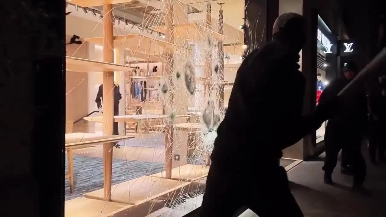 Đám đông đập kính mãi không vỡ khi nhắm vào cửa hàng Louis Vuitton.