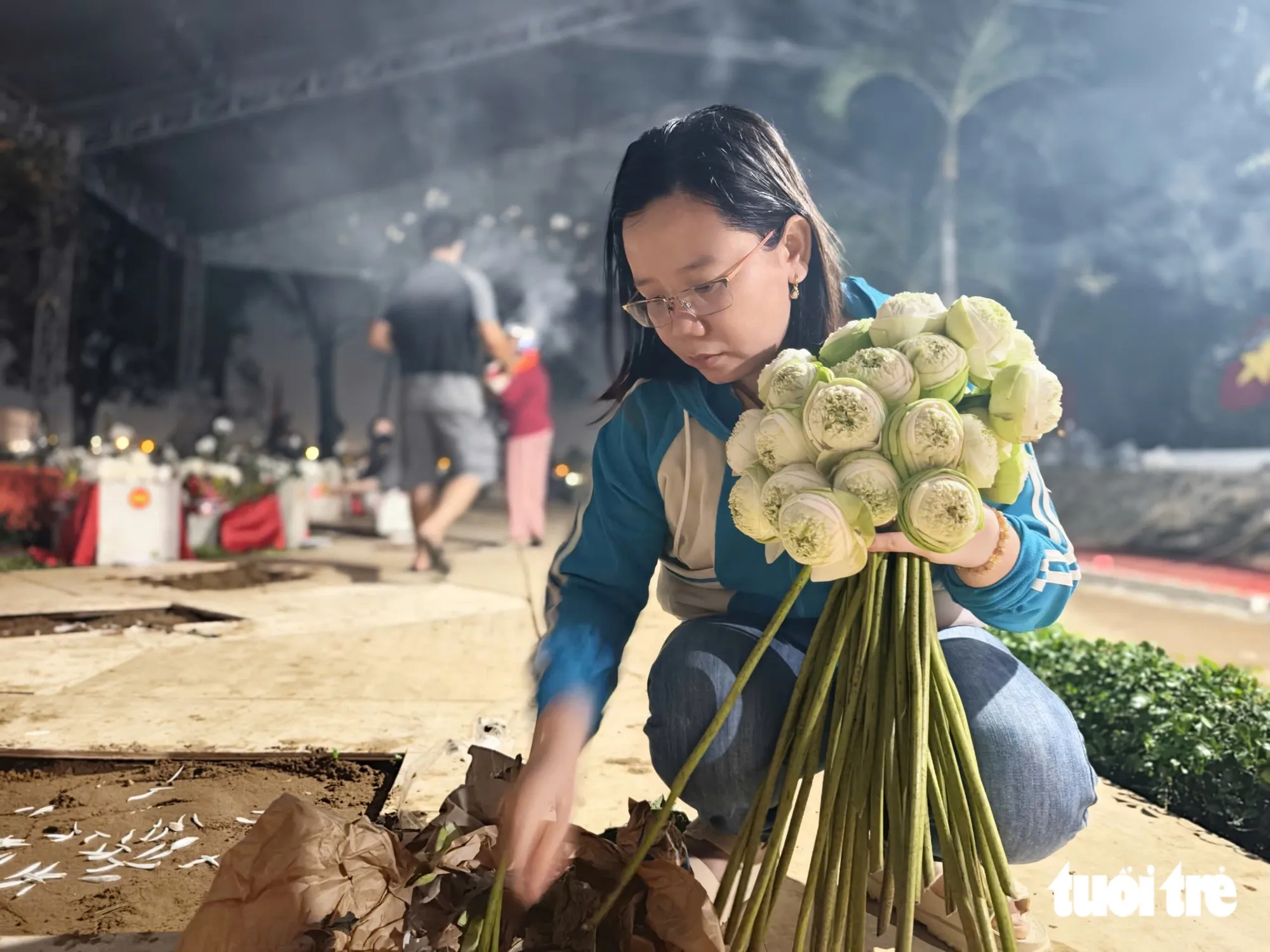 Chị Trang Thị Thanh Kiều tranh thủ tan giờ làm đến dâng những bó hoa lên các anh hùng liệt sĩ - Ảnh: TRÍ ĐỨC