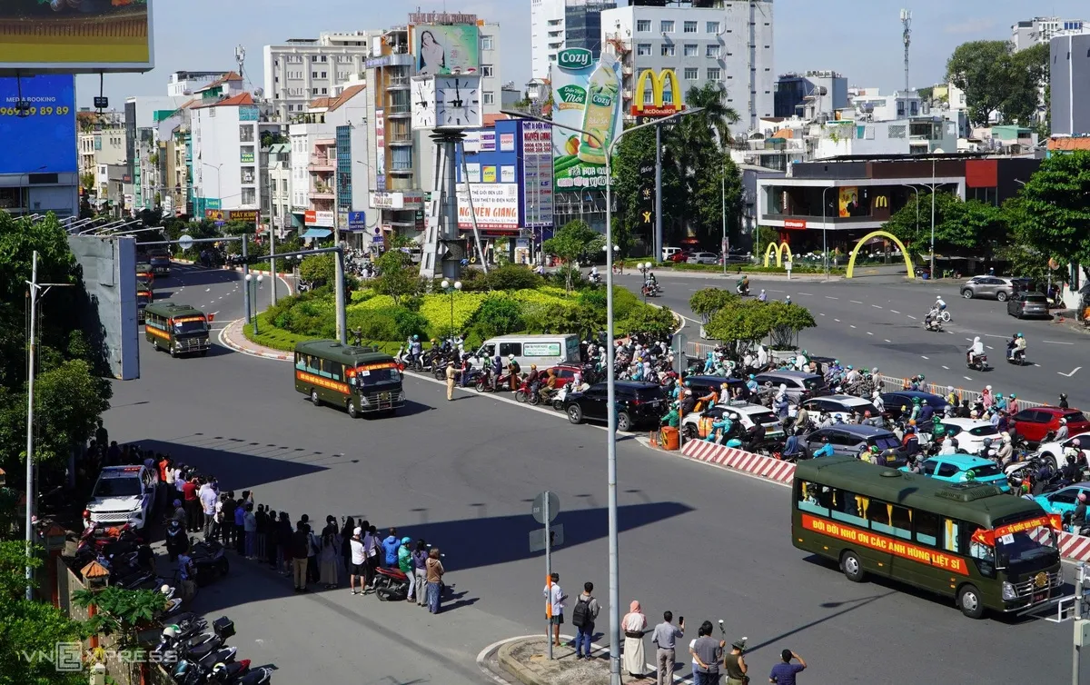 Đoàn xe qua vòng xoay Nguyễn Bỉnh Khiêm - Điện Biên Phủ (quận 1 cũ), hướng về cầu Sài Gòn.
Sáng nay, lực lượng Bộ Tư lệnh TP HCM gắn hoa trắng dọc thành cầu. Trên đường Điện Biên Phủ, các đơn vị chức năng túc trực phân luồng, hướng dẫn xe lưu thông.
