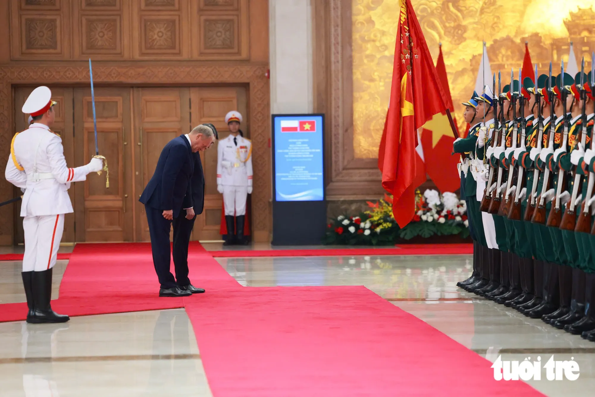 Thủ tướng Lê Minh Hưng và Thủ tướng Ba Lan Donald Tusk cúi chào quân kỳ Quân đội nhân dân Việt Nam - Ảnh: NGUYỄN KHÁNH