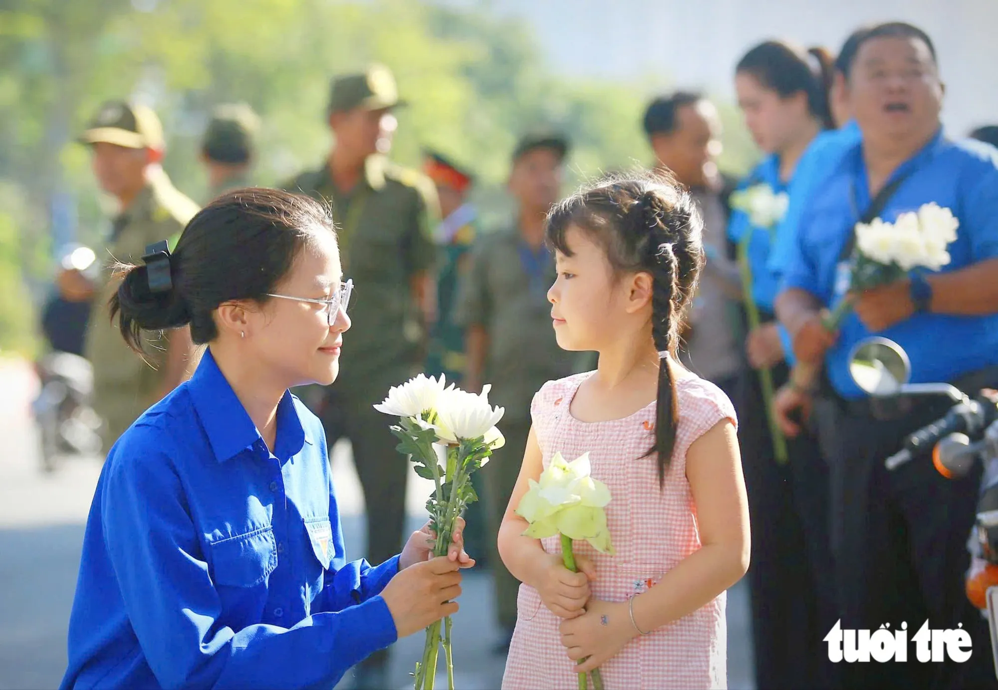 Đoàn phường, Mặt trận Tổ quốc phường An Khánh tặng hoa miễn phí cho người dân chờ đưa tiễn đoàn xe đưa liệt sĩ. Ảnh chụp dưới ga Thảo Điền - Ảnh: CHÂU TUẤN