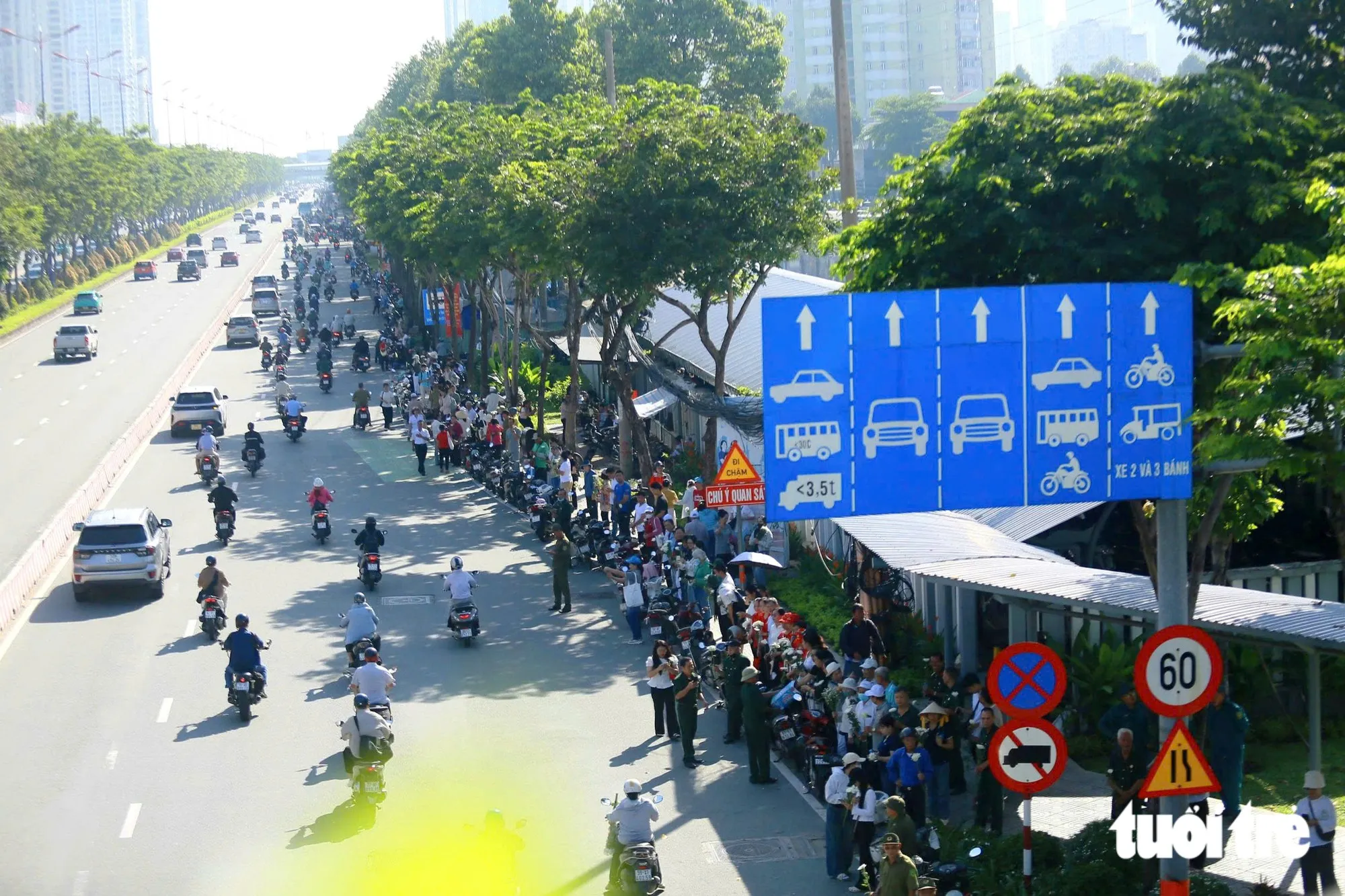Hoa trắng trên tay người dân đứng hai bên tuyến đường sẽ đưa các anh về Nghĩa trang liệt sĩ TP.HCM - Ảnh: CHÂU TUẤN
