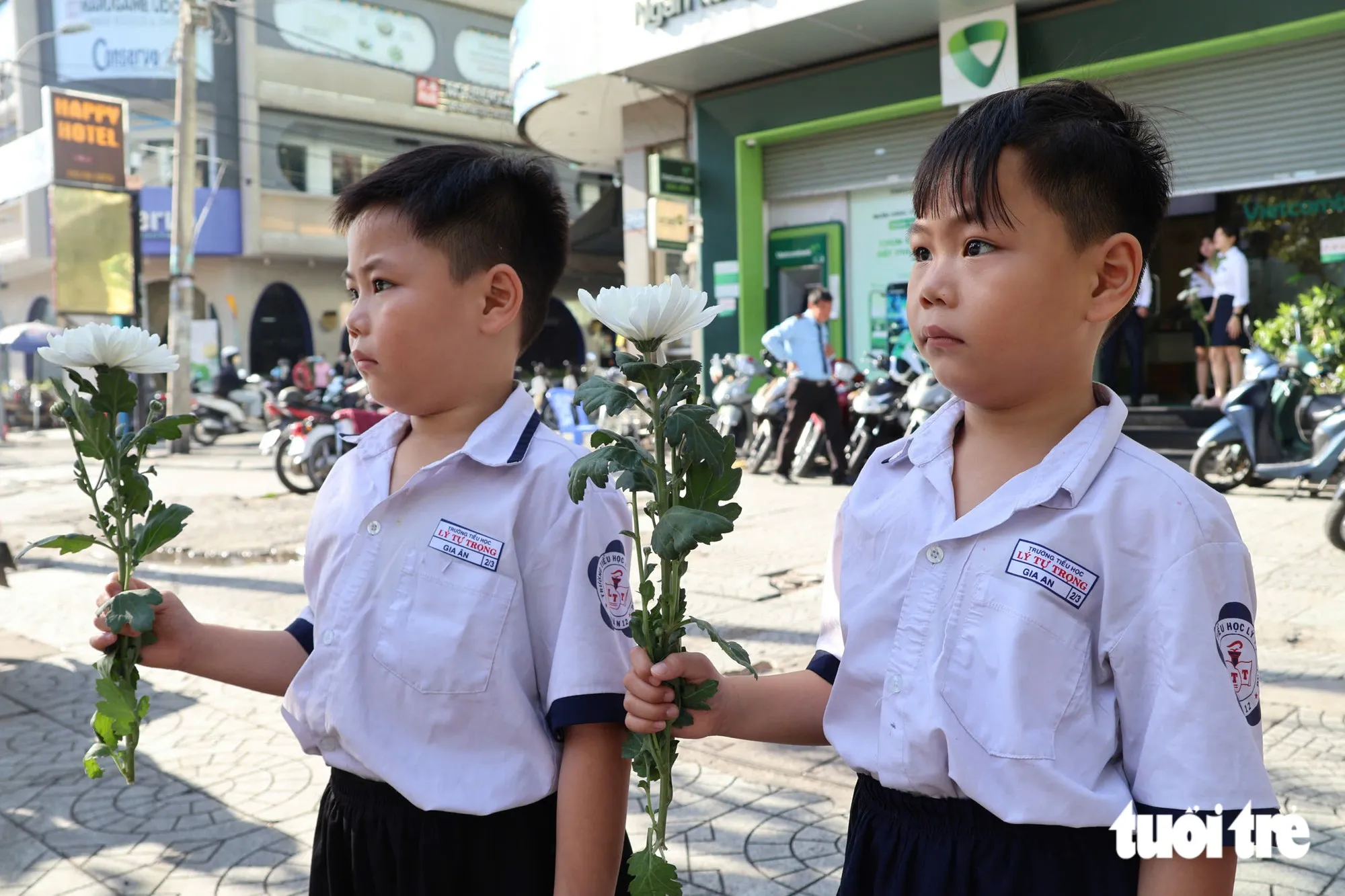 Hai anh em Gia Ân và Gia An, học sinh lớp 2, xin nghỉ học một ngày để có mặt tiễn đưa các anh hùng liệt sĩ. Các em bày tỏ lòng biết ơn trước sự hy sinh của các thế hệ đi trước - Ảnh: ĐẶNG LINH