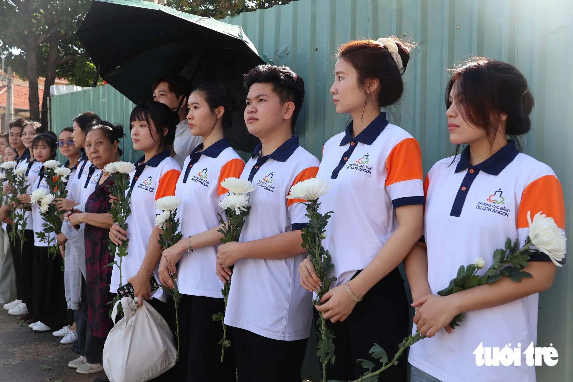 Sinh viên Trường cao đẳng Du lịch Sài Gòn cùng bà con có mặt tại vòng xoay Dân Chủ cùng nhành hoa trắng để tiễn đưa các anh - Ảnh: ĐẶNG LINH