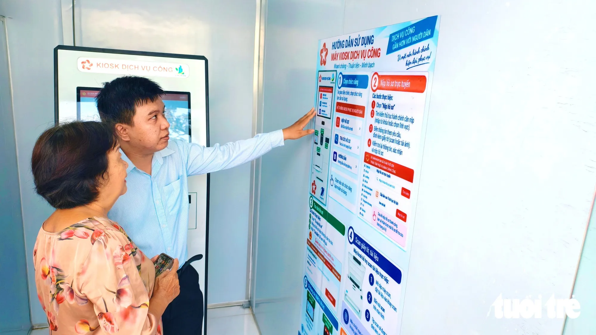 Bà Nguyễn Thị Reo (63 tuổi) được hướng dẫn sử dụng máy kiosk dịch vụ công tại Trạm tiện ích số 24/7. Bà Reo chia sẻ: