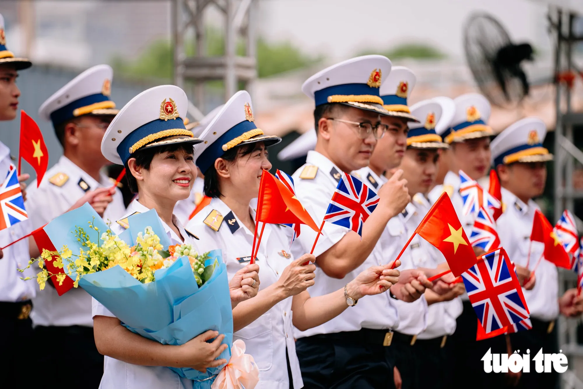 Các đại biểu Quân đội Nhân dân Việt Nam vẫy cờ hai nước Việt Nam - Anh chào đón tàu Hải quân Anh cập cảng Nhà Rồng trưa 22-10 - Ảnh: THANH HIỆP