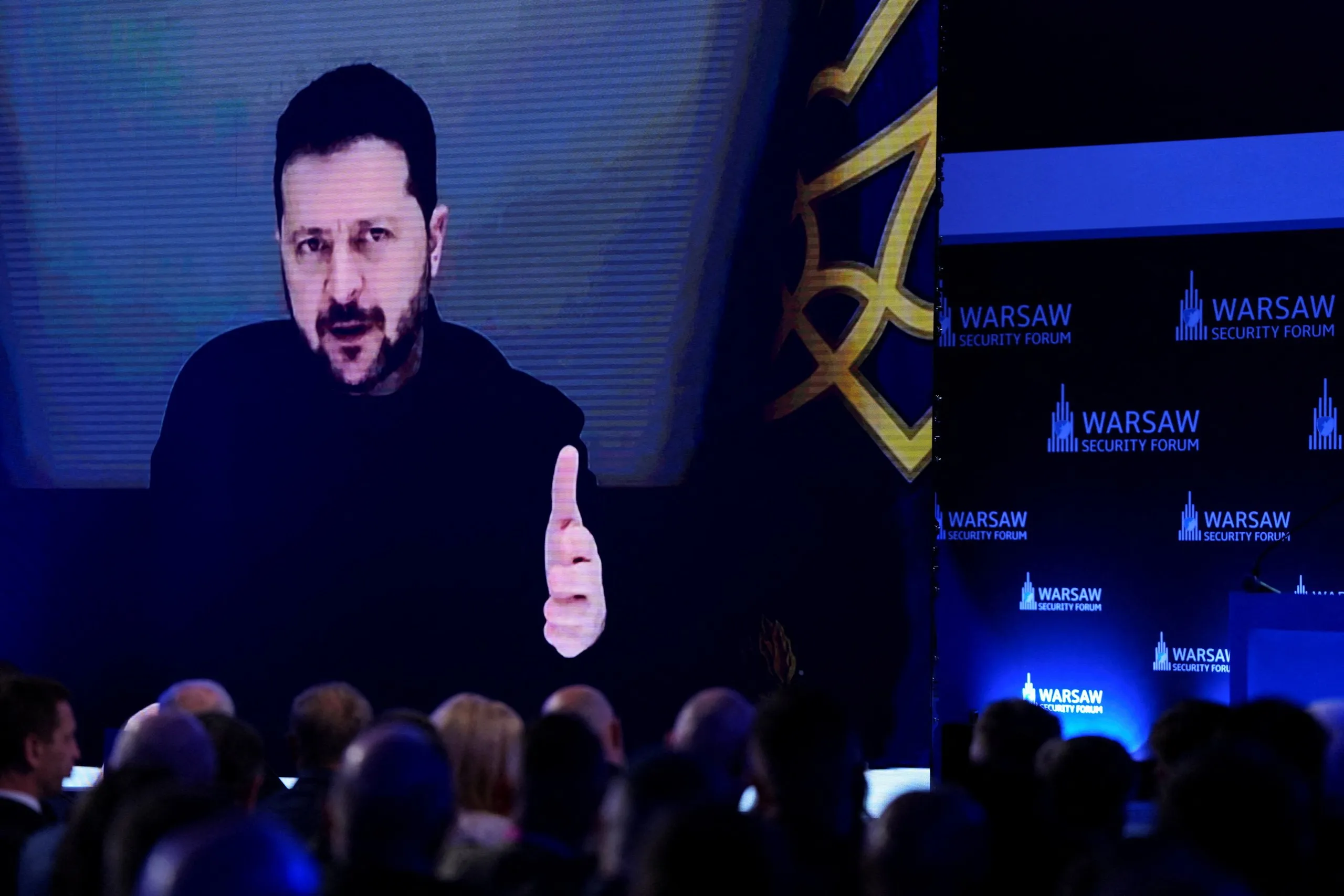 Tổng thống Ukraine Volodymyr Zelensky xuất hiện trên màn hình khi phát biểu tại Diễn đàn An ninh Warsaw ở Ba Lan - Ảnh: REUTERS