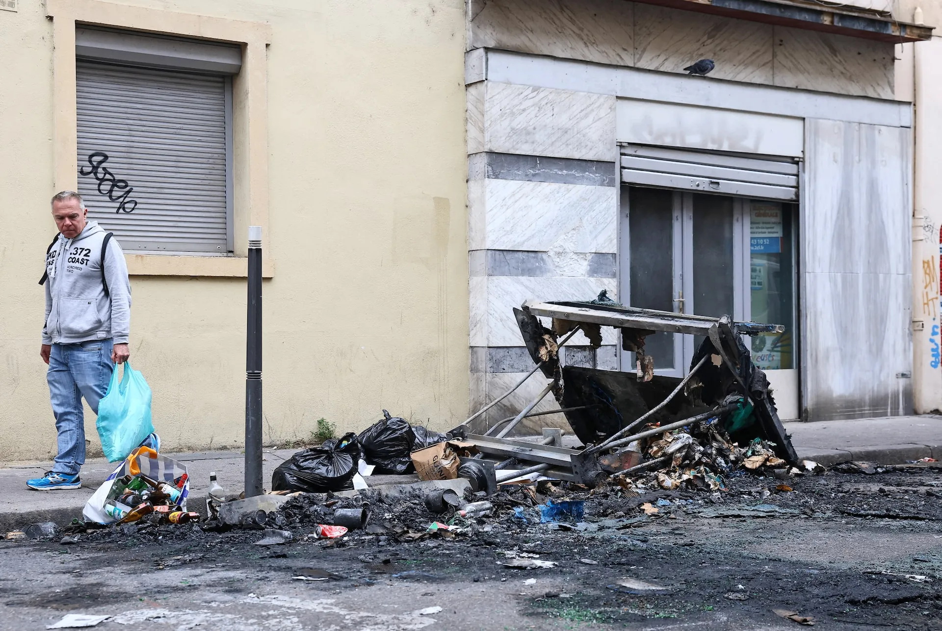 Một người quan sát đống đổ nát bị cháy sau các cuộc đụng độ tại Lyon (Pháp) ngày 25-10 - Ảnh: REUTERS