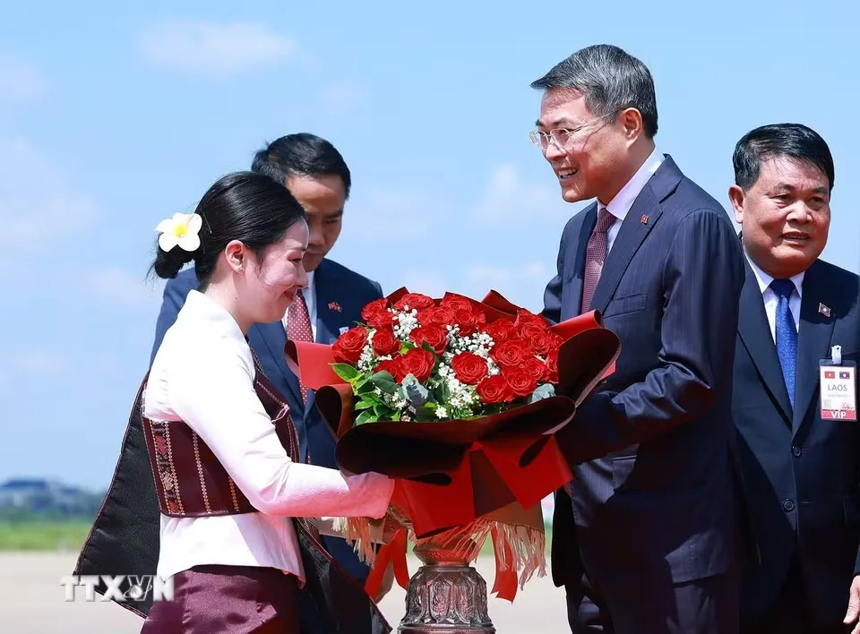 Thủ tướng Lê Minh Hưng nhận bó hoa tươi thắm khi đến thủ đô Vientiane, bắt đầu chuyến thăm chính thức Lào - Ảnh: TTXVN
