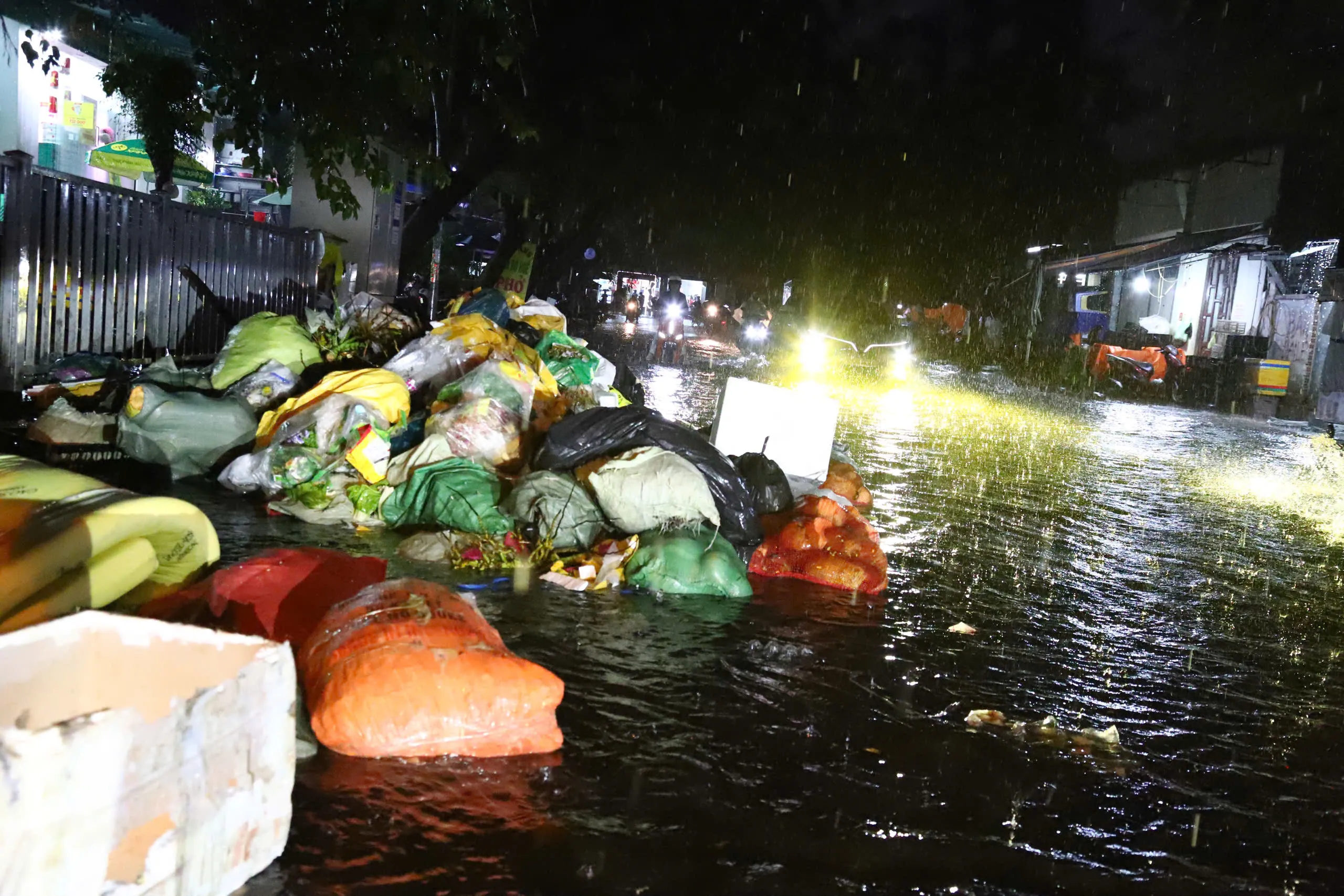 Mưa to, nước lớn cuốn rác trên vỉa hè tại khu chợ Tân Sơn Nhất (phường Hạnh Thông) ra đường - Ảnh: NGỌC LÂN