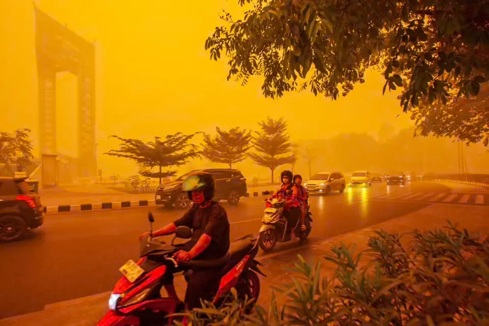 Người đi xe máy di chuyển trong làn khói mù dày đặc do cháy rừng gây ra ở Palangkaraya, Indonesia. Các vụ cháy rừng tại Kalimantan và Sumantra do hiện tượng El Nino đã làm khiến khói mù độc hại lan ra khắp khu vực, bao gồm cả các nước láng giềng như Malaysia và Singapore. Tại Indonesia, hàng trăm ngàn người bị ảnh hưởng sức khỏe vì cháy rừng đợt này - Ảnh: EPA