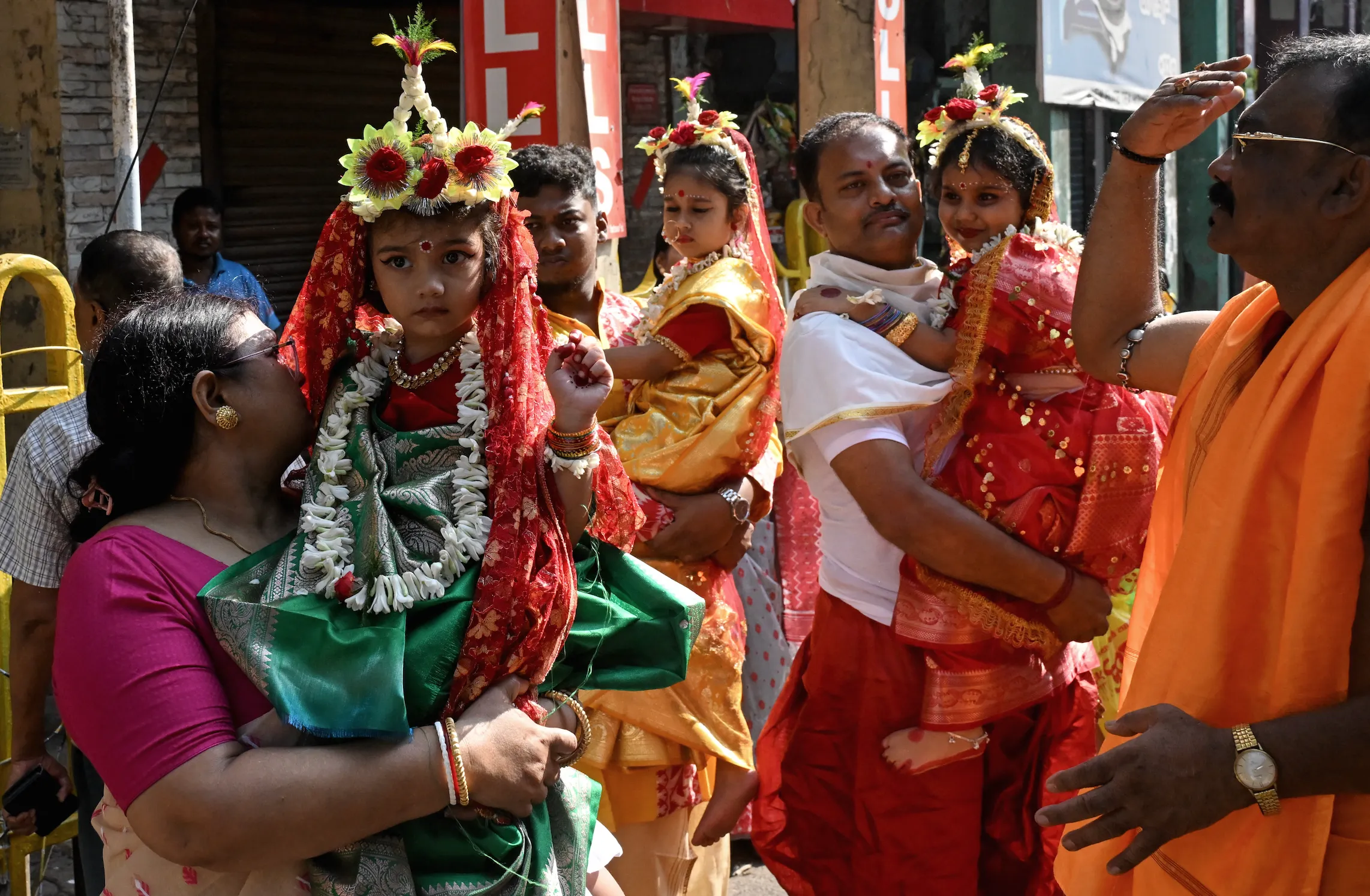 Các tín đồ đạo Hindu bế những bé gái hóa thân thành nữ thần Durga của đạo Hindu tại lễ hội Durga Puja diễn ra ở Kolkata, Ấn Độ tuần này. Truyền thống này nhằm tôn vinh phẩm giá, giá trị và sự thiêng liêng của người phụ nữ - Ảnh: AFP