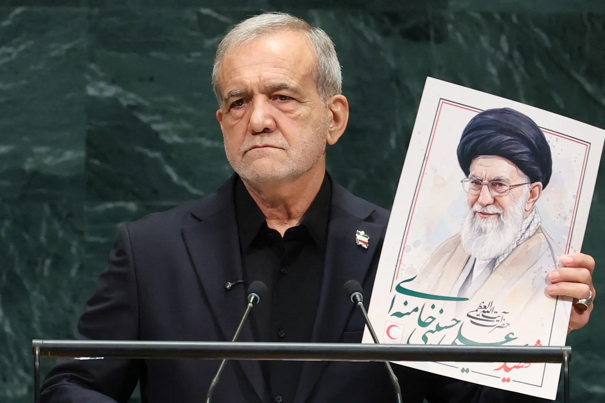 Tổng thống Iran Masoud Pezeshkian cầm ảnh cố lãnh tụ tối cao Ali Khamenei khi phát biểu tại Đại hội đồng Liên hợp quốc ở New York ngày 23-9 - Ảnh: AFP