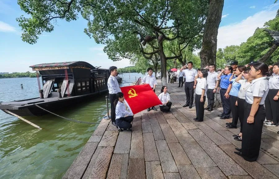 Các đảng viên Đảng Cộng sản Trung Quốc ôn lại lời tuyên thệ kết nạp Đảng bên cạnh bản sao của con thuyền, nay được gọi là Thuyền Đỏ, vào tháng 6-2025. Đây là nơi các nhà sáng lập Đảng Cộng sản Trung Quốc bế mạc hội nghị vào năm 1921 - Ảnh: TÂN HOA XÃ